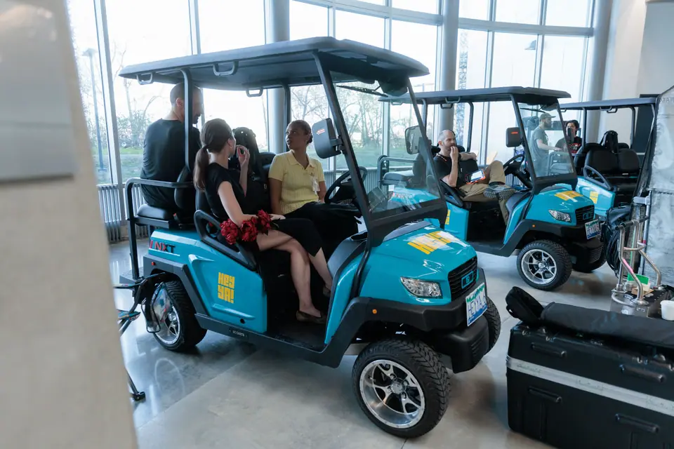 Cast and crew seated in HeyYa carts inside a glass atrium during a film shoot