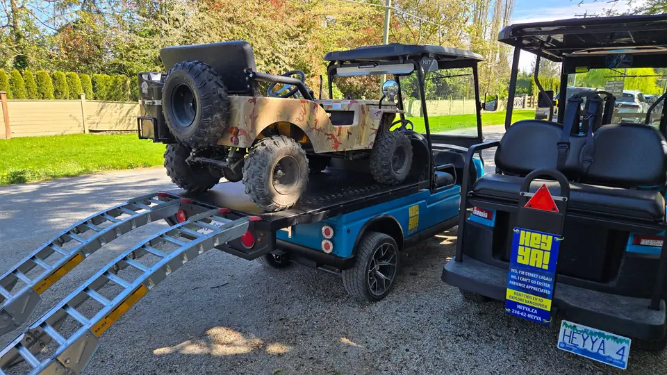 A HeyYa electric flatdeck carrying a small off-road vehicle, with loading ramps lowered behind it