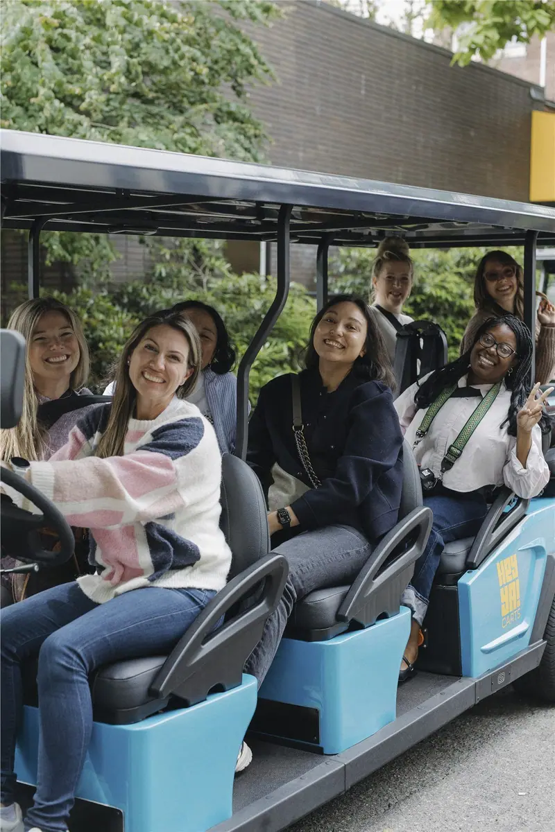 Friends smiling together aboard a blue HeyYa cart