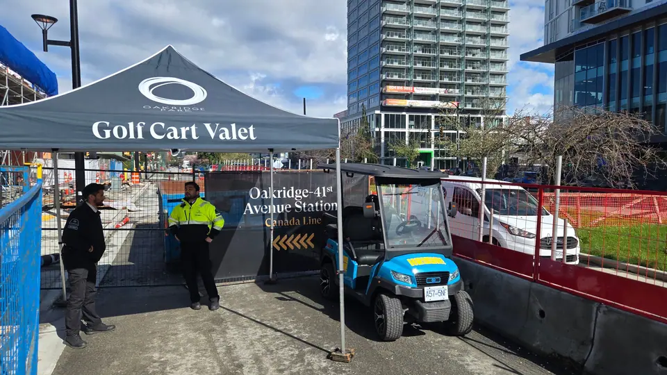A HeyYa cart parked beside a branded golf cart valet tent at a Vancouver development site