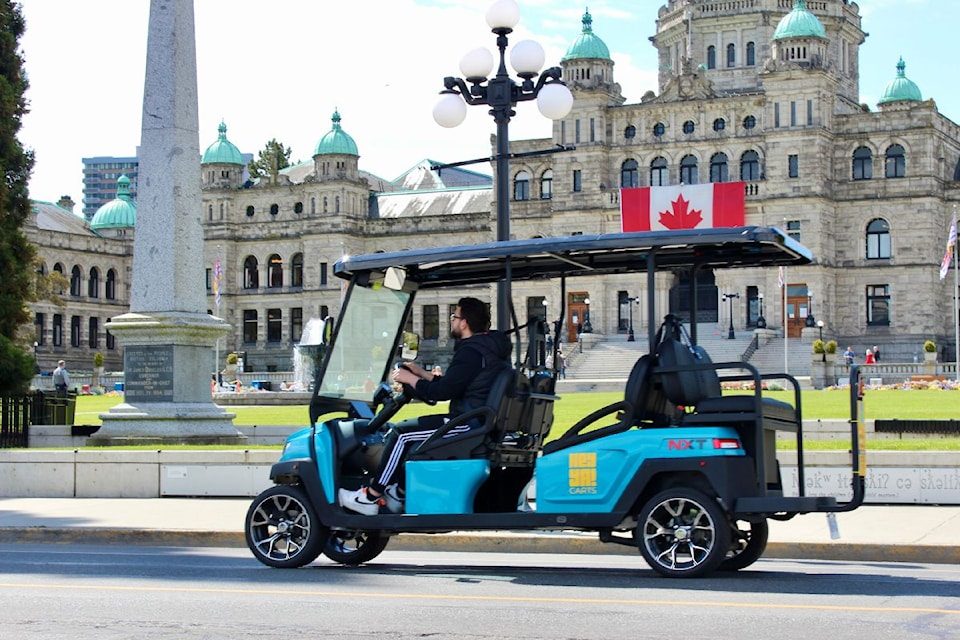 A HeyYa cart flying a Canadian flag in front of the BC Parliament Buildings