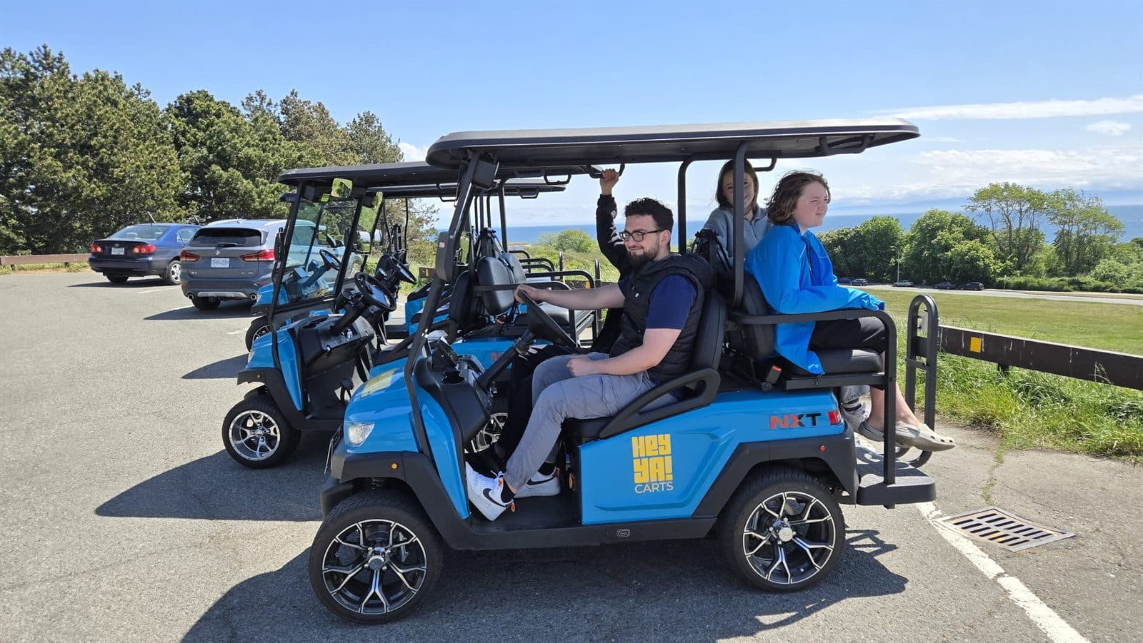 Passengers riding HeyYa carts along a Victoria waterfront road